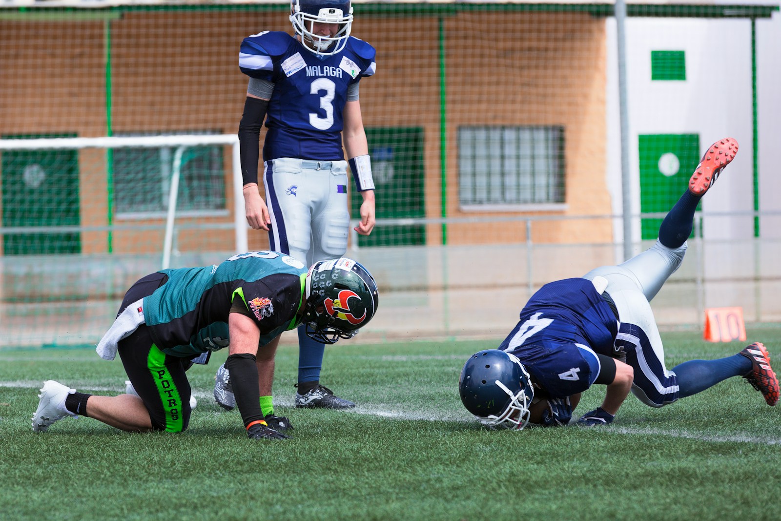 three American football standing on grass field