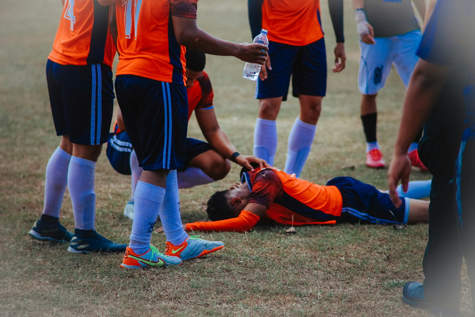 a group of soccer players standing around a man on the ground